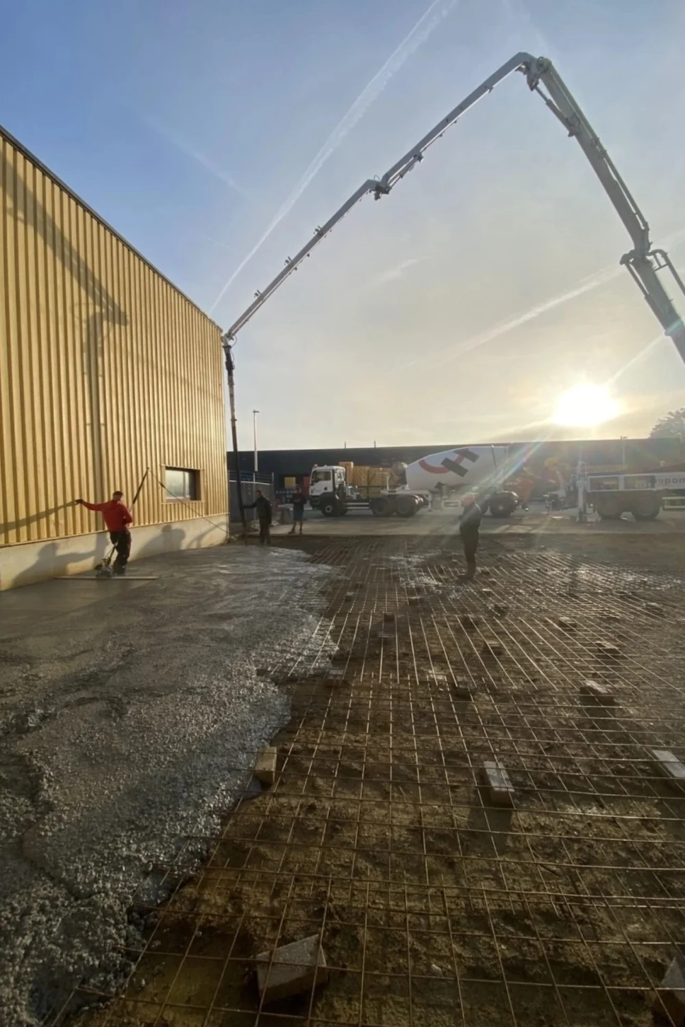 Coulage d’une dalle en béton sur chantier industriel en Wallonie, réalisé par LADCO avec pompe et armature pour assurer solidité et durabilité du sol.